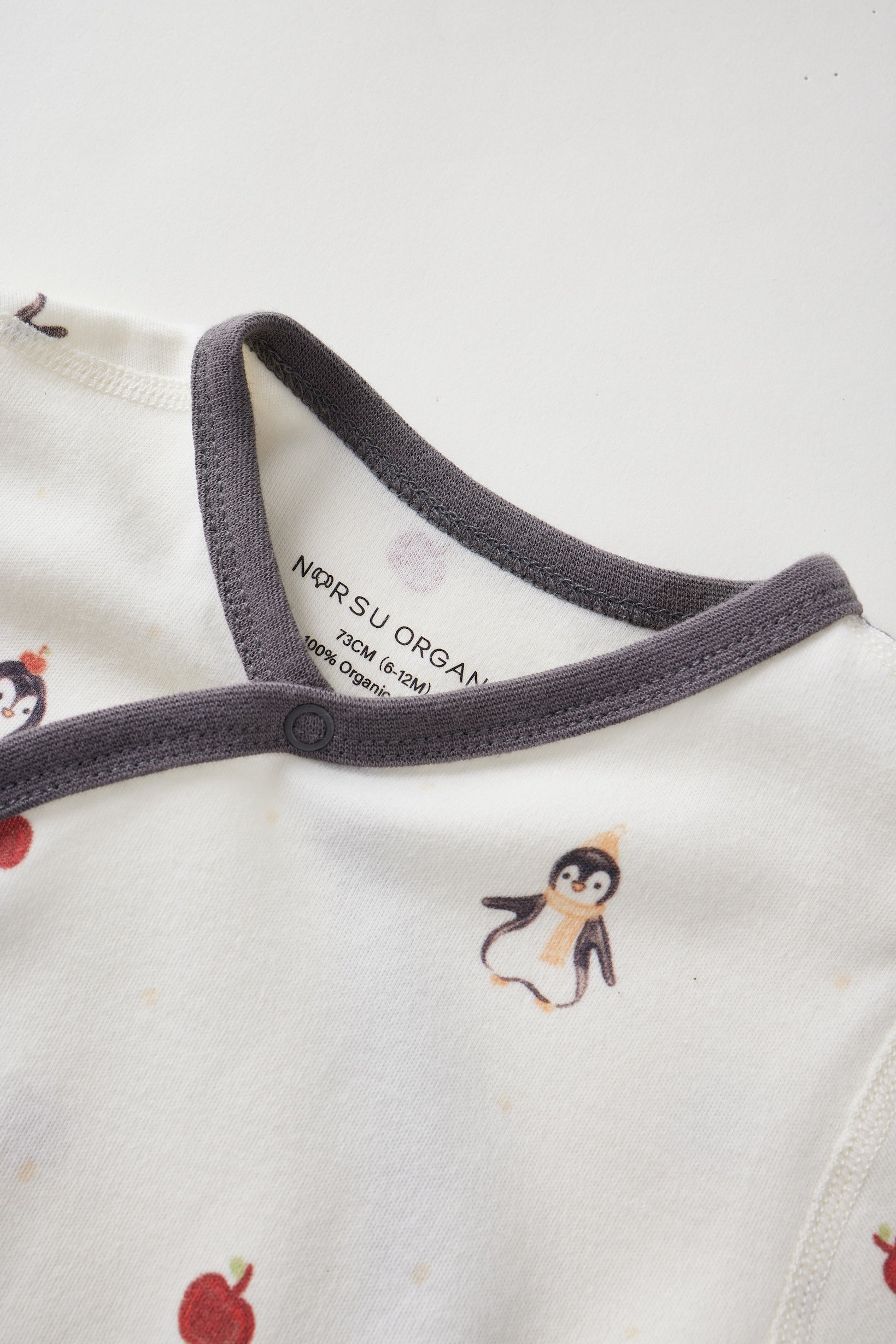 Close-up of a baby outfit with penguin design and visible brand label on a white background
