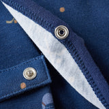 Close-up of a blue garment with buttons and embroidered details