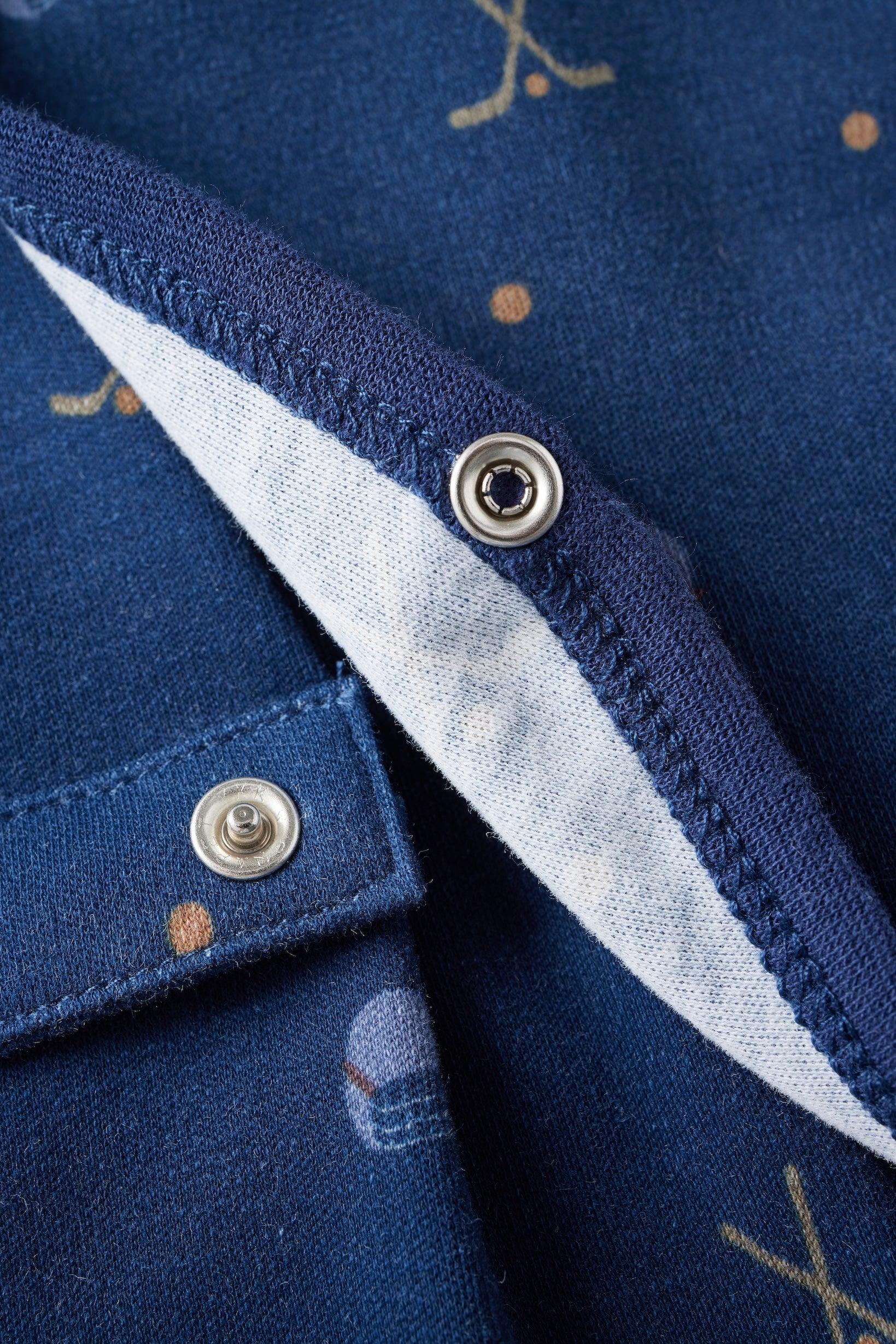 Close-up of a blue garment with buttons and embroidered details