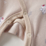 Close-up of a beige baby onesie with button details and small animal prints.
