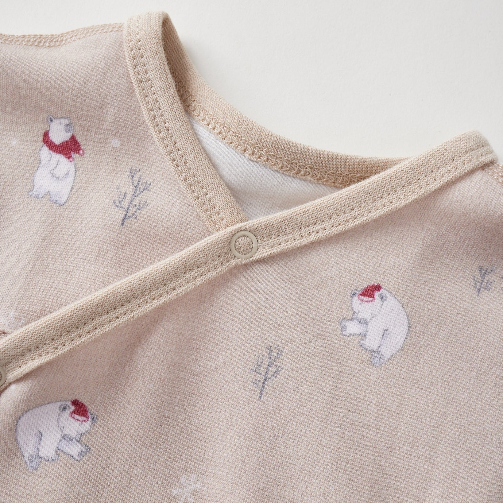 Beige baby sleeper with polar bear and snowflake pattern on a light background