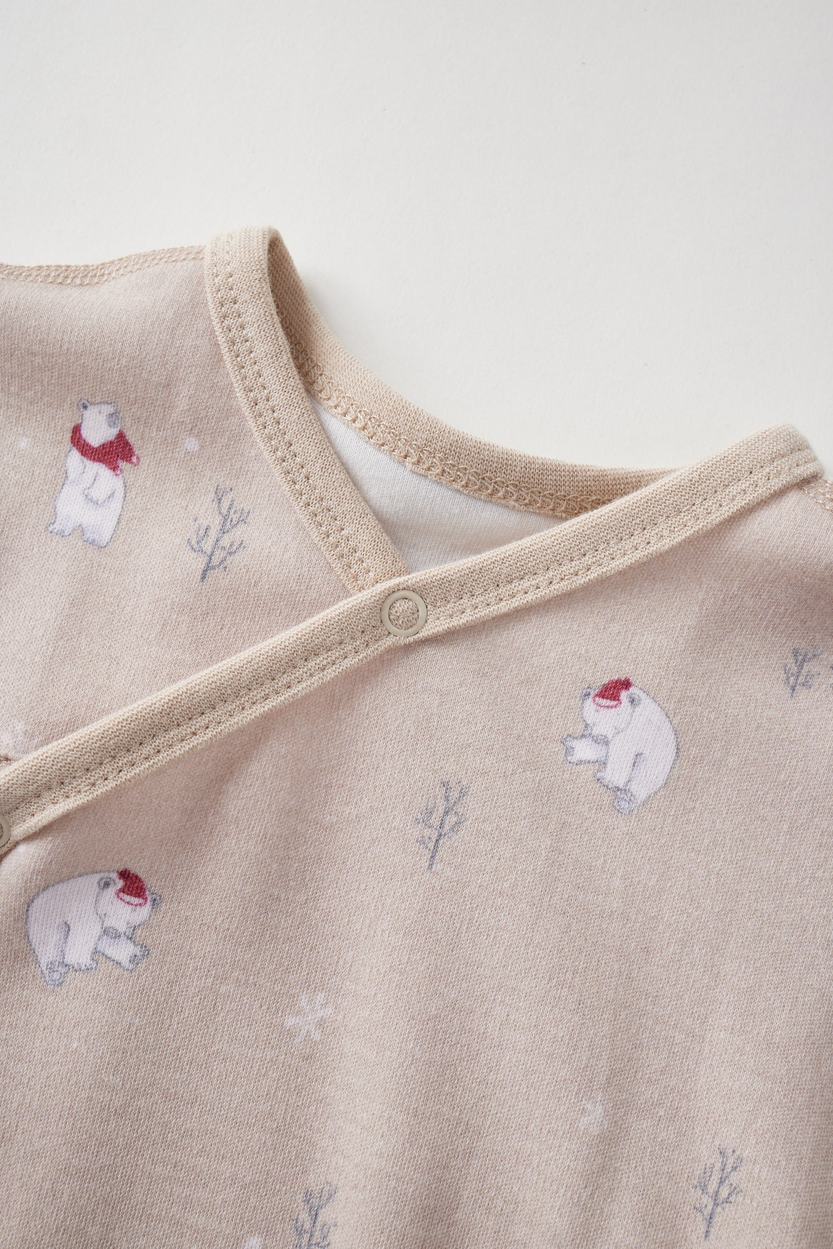 Beige baby sleeper with polar bear and snowflake pattern on a light background