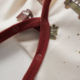 Close-up of a red strap on a garment with a pattern of brown cars on a beige background.