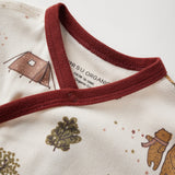 Close-up of a baby outfit with red collar and nature-themed design on a white background