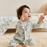 Baby in jolly pajamas sitting on a carpeted floor