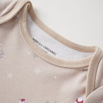 Close-up of a beige baby onesie with polar bear designs and 'Norsu Organic' label.