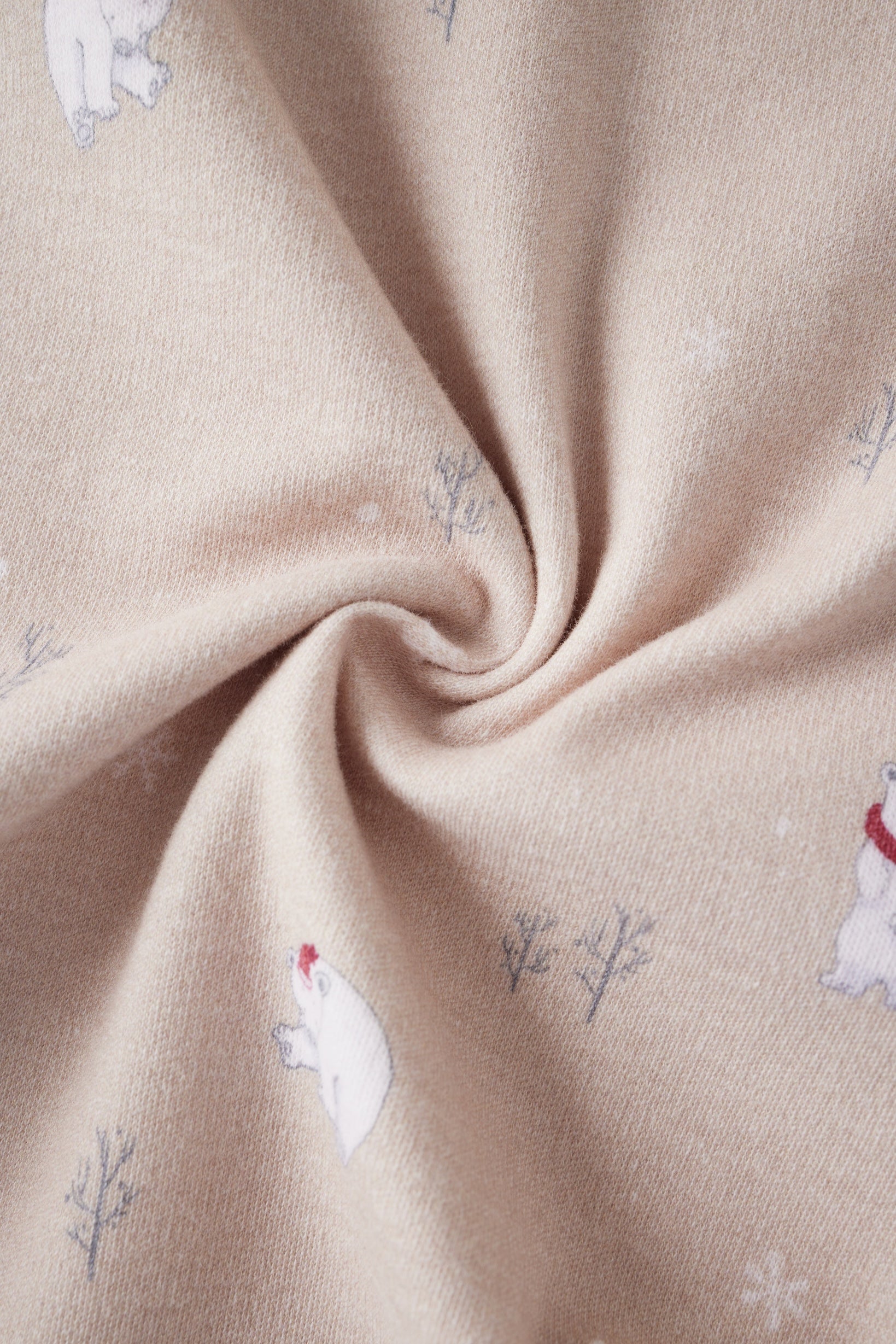 Close-up of beige fabric with embroidered polar bear and tree patterns