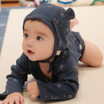 Baby wearing a navy blue onesie outfit on a beige surface