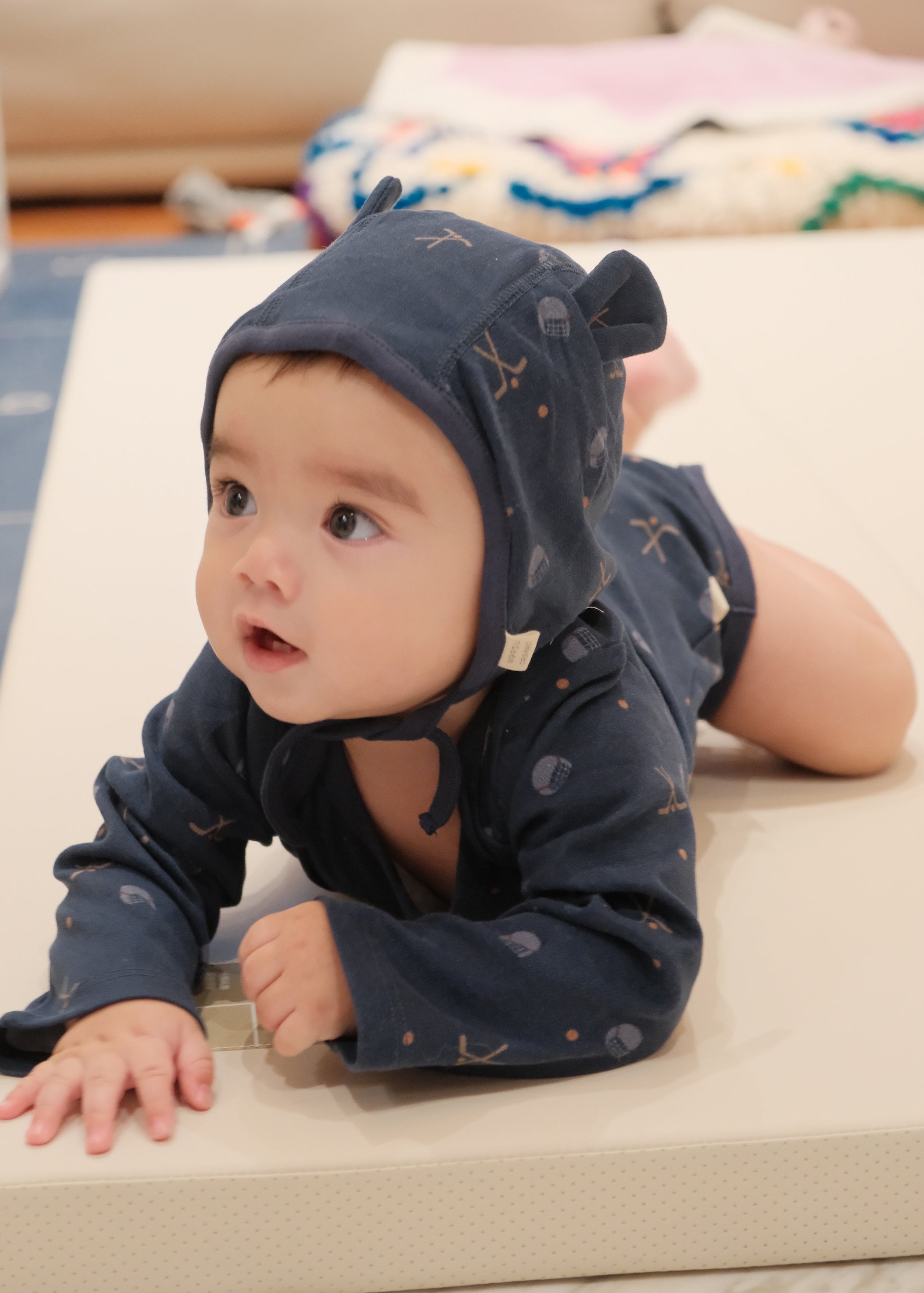 Baby wearing a navy blue onesie outfit on a beige surface