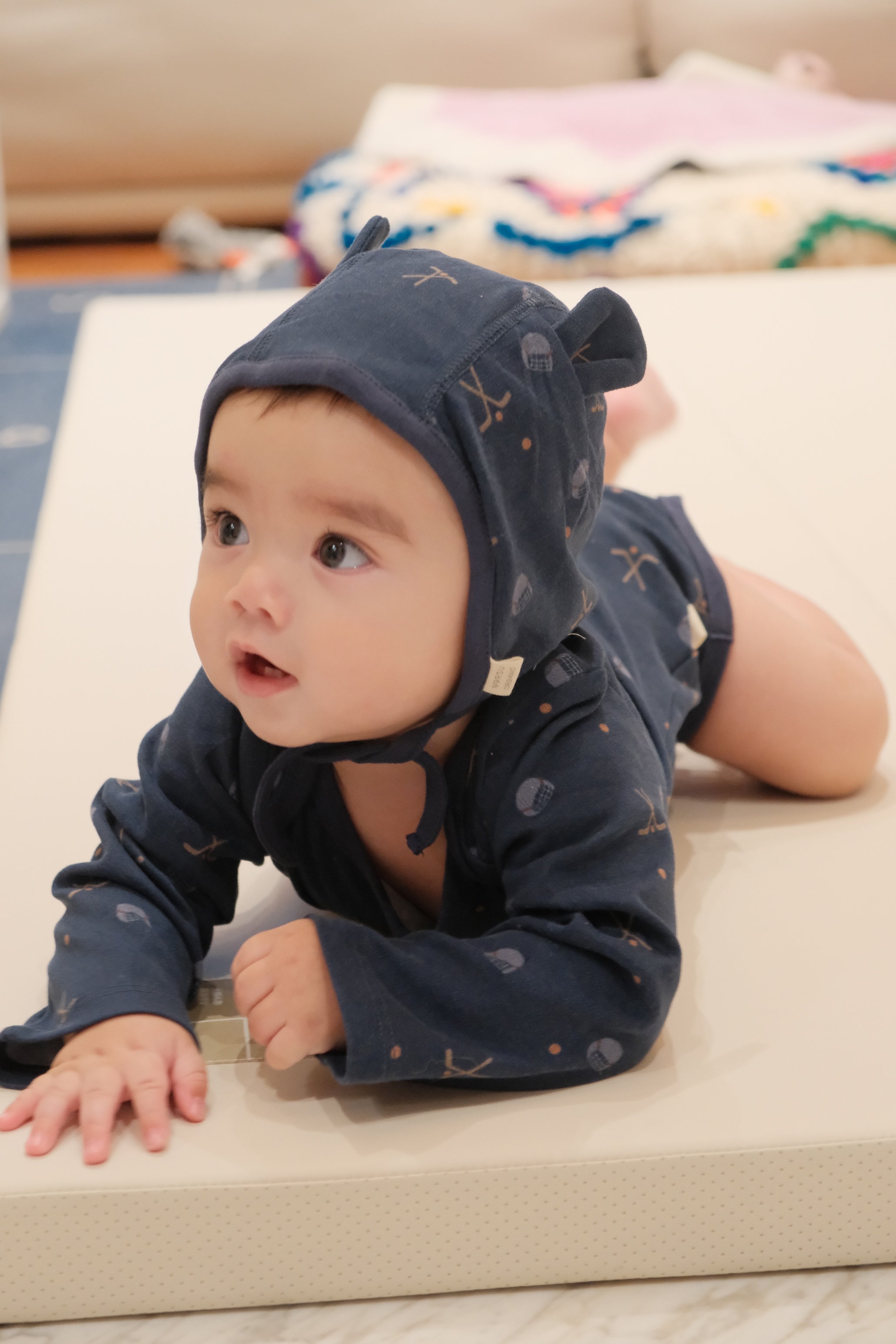 Baby wearing a navy blue onesie outfit on a beige surface