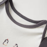 Close-up of a baby outfit with embroidered penguins and gray trim on a white background