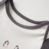 Close-up of a baby outfit with embroidered penguins and gray trim on a white background