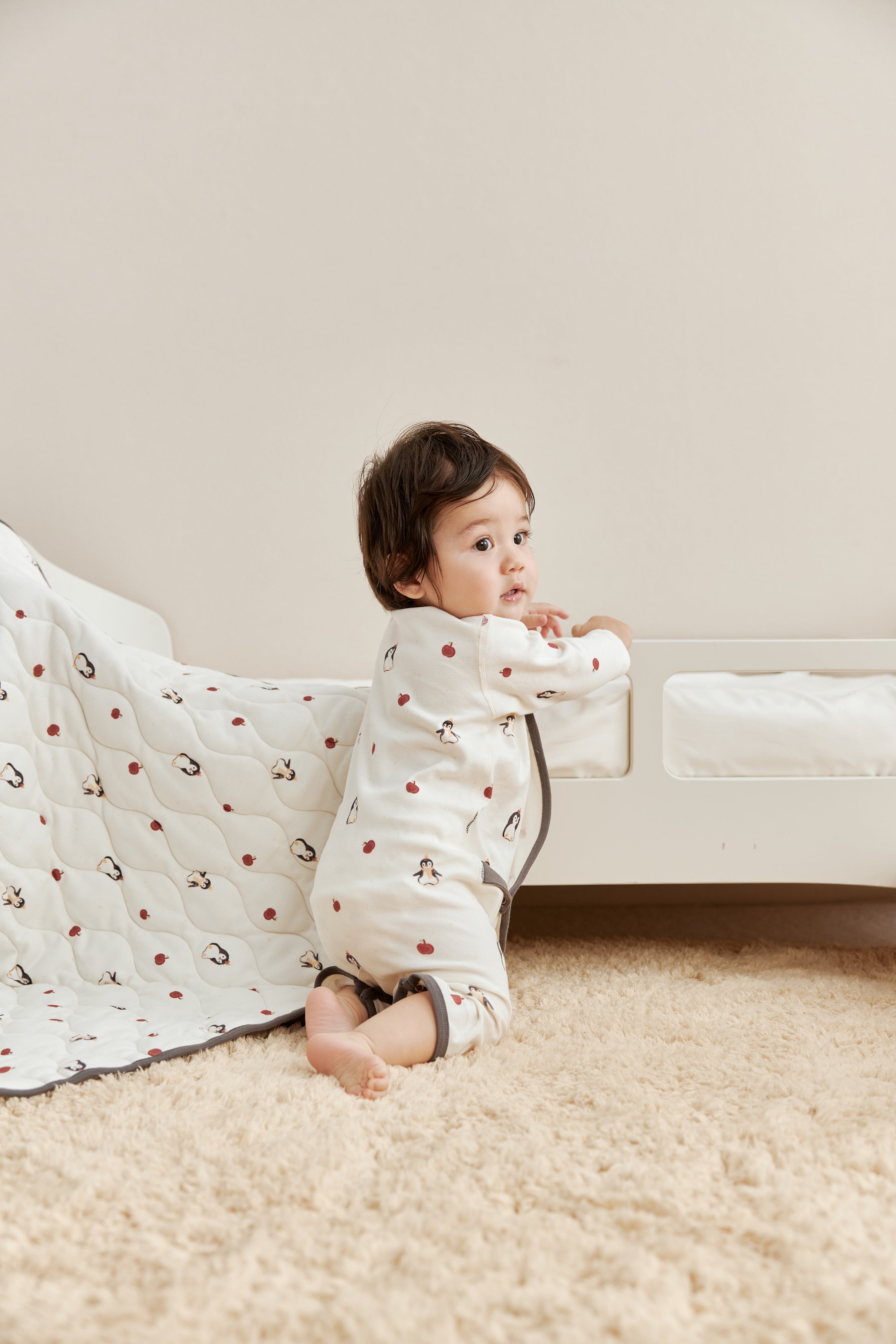 Child sitting on a carpeted floor wearing a patterned outfit.