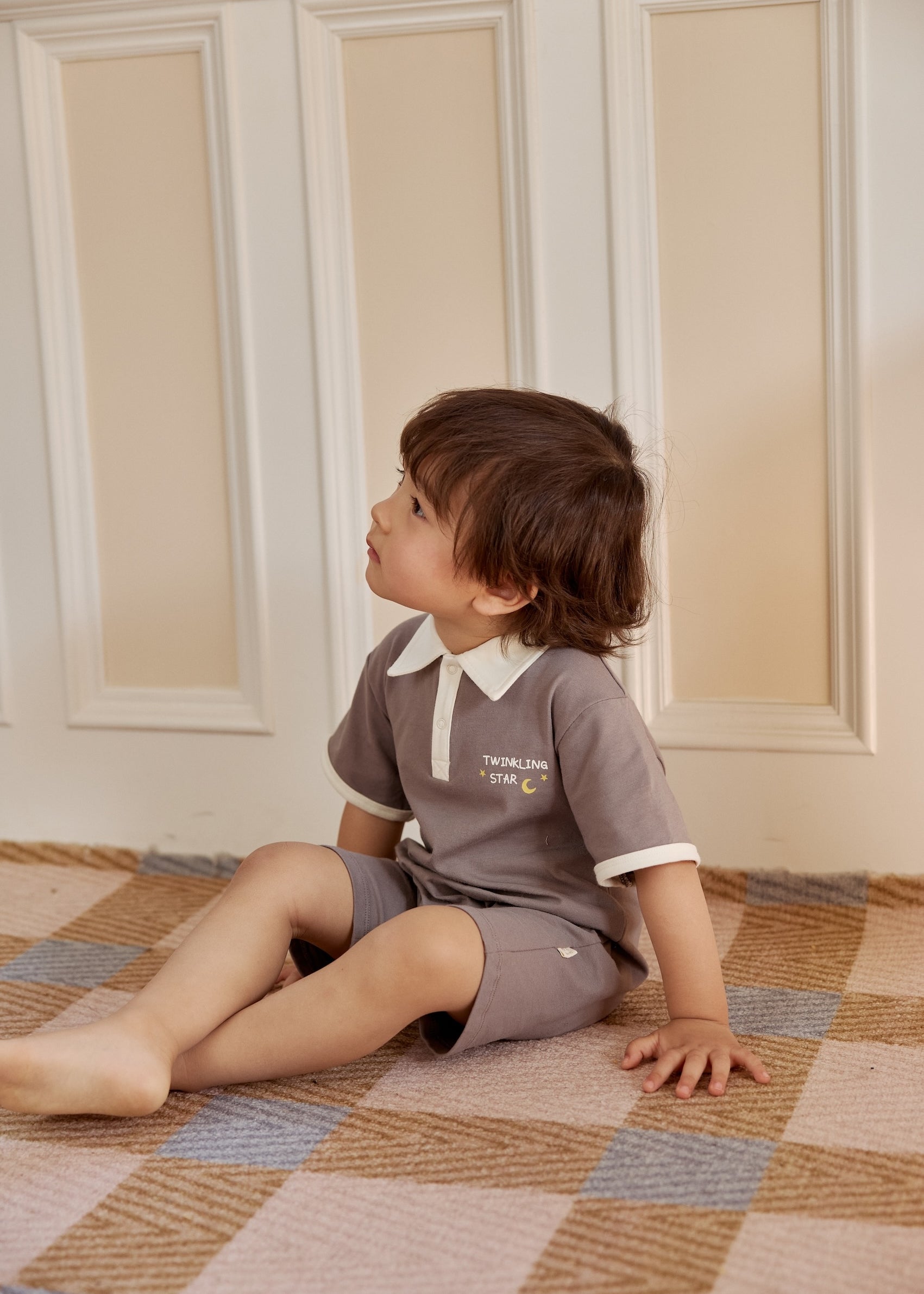baby boy sitting on the floor and wearing norsu organic Baby Polo Romper-Dark Grey 