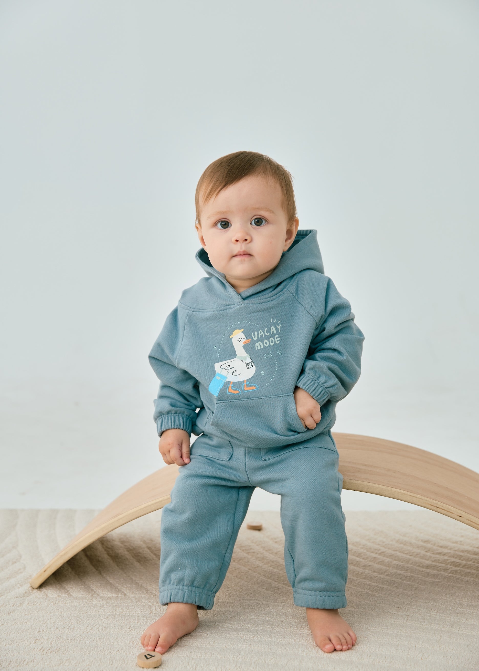 baby sitting on the chair and wearing Toddler Organic Hooded Sweatshirt-Travel duck