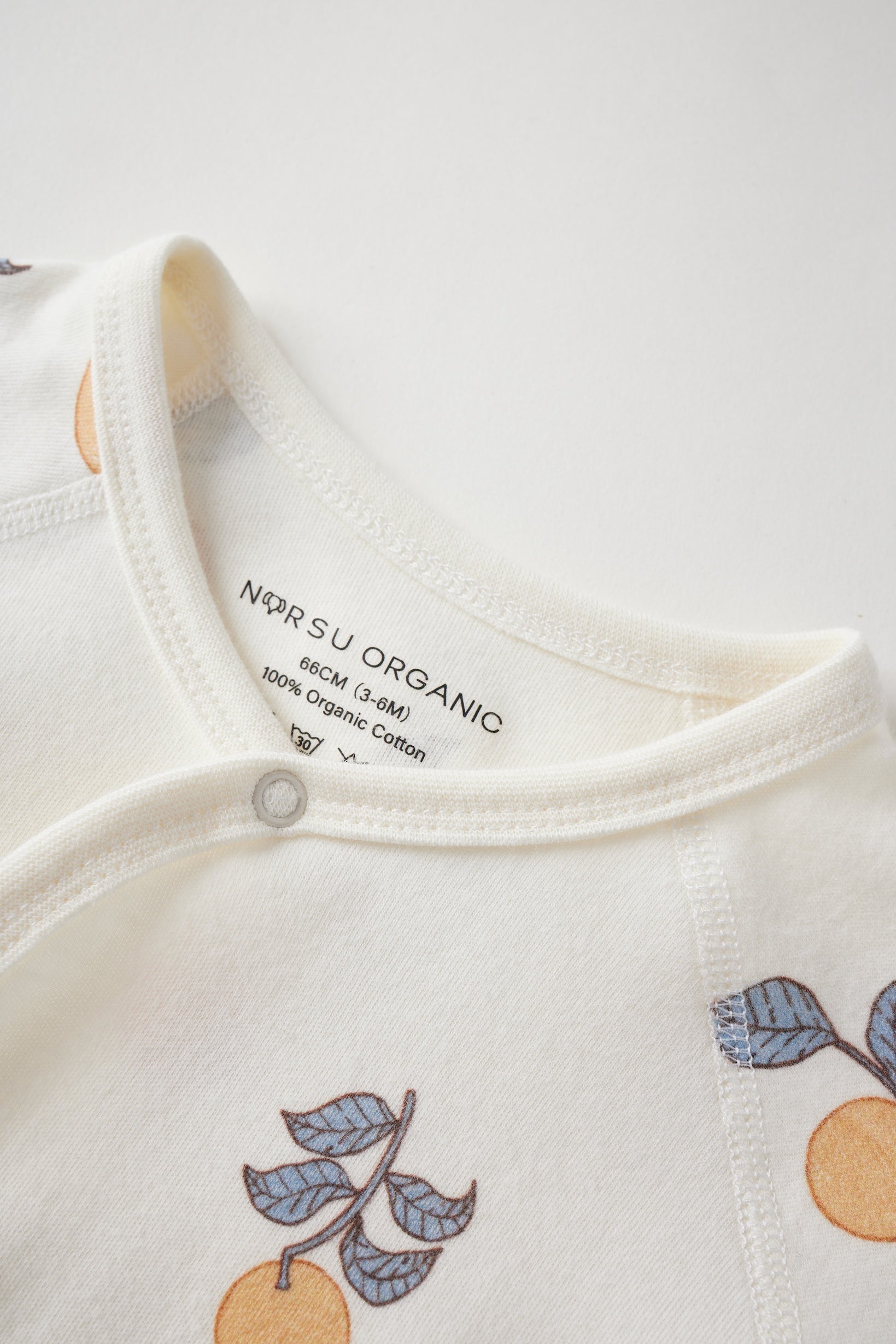 Close-up of a baby outfit with 'NORSU ORGANIC' label on a white background
