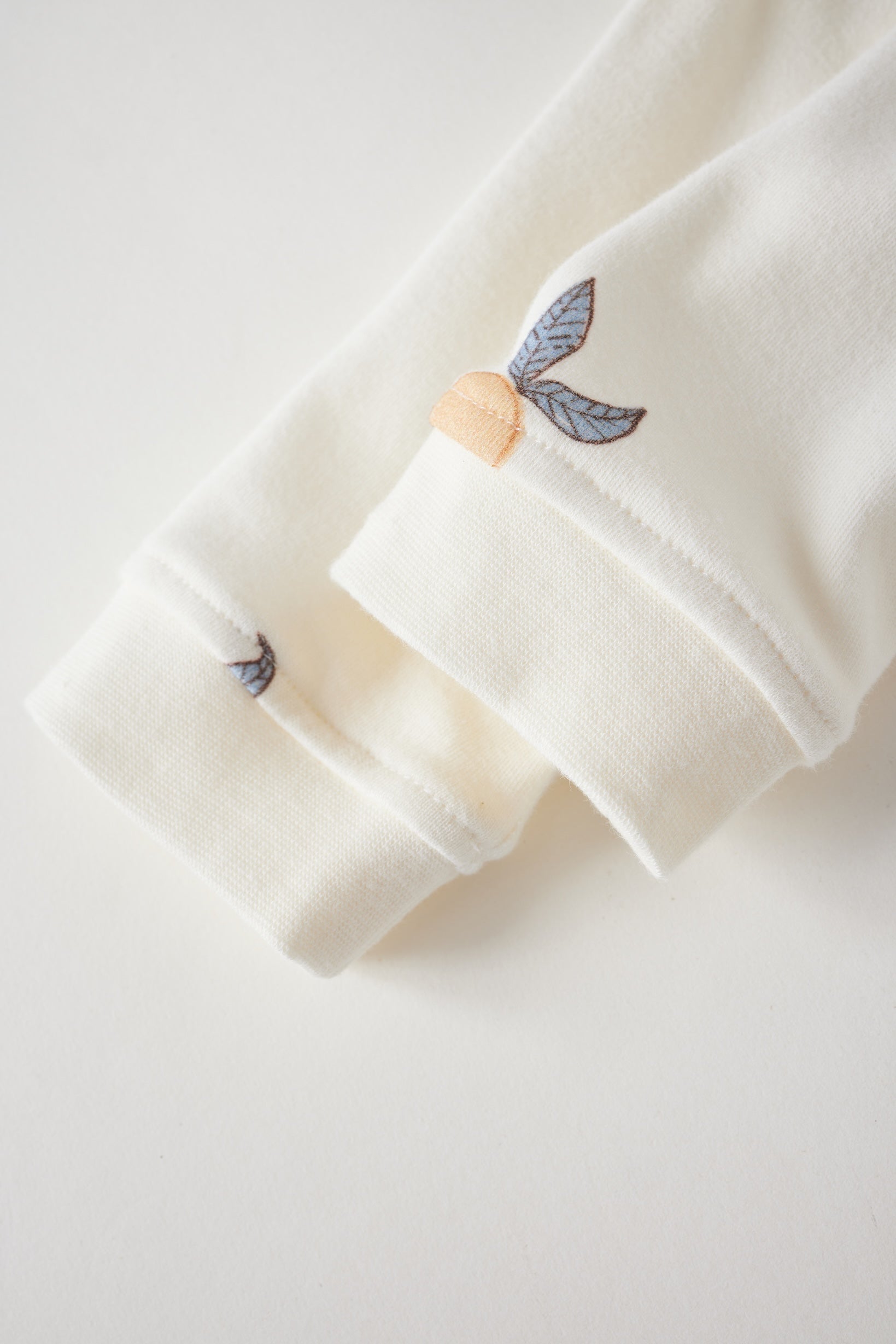 Close-up of a white garment with embroidered butterfly details on a light gray background