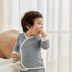 Child wearing a blue starry outfit with white trim in a bright room