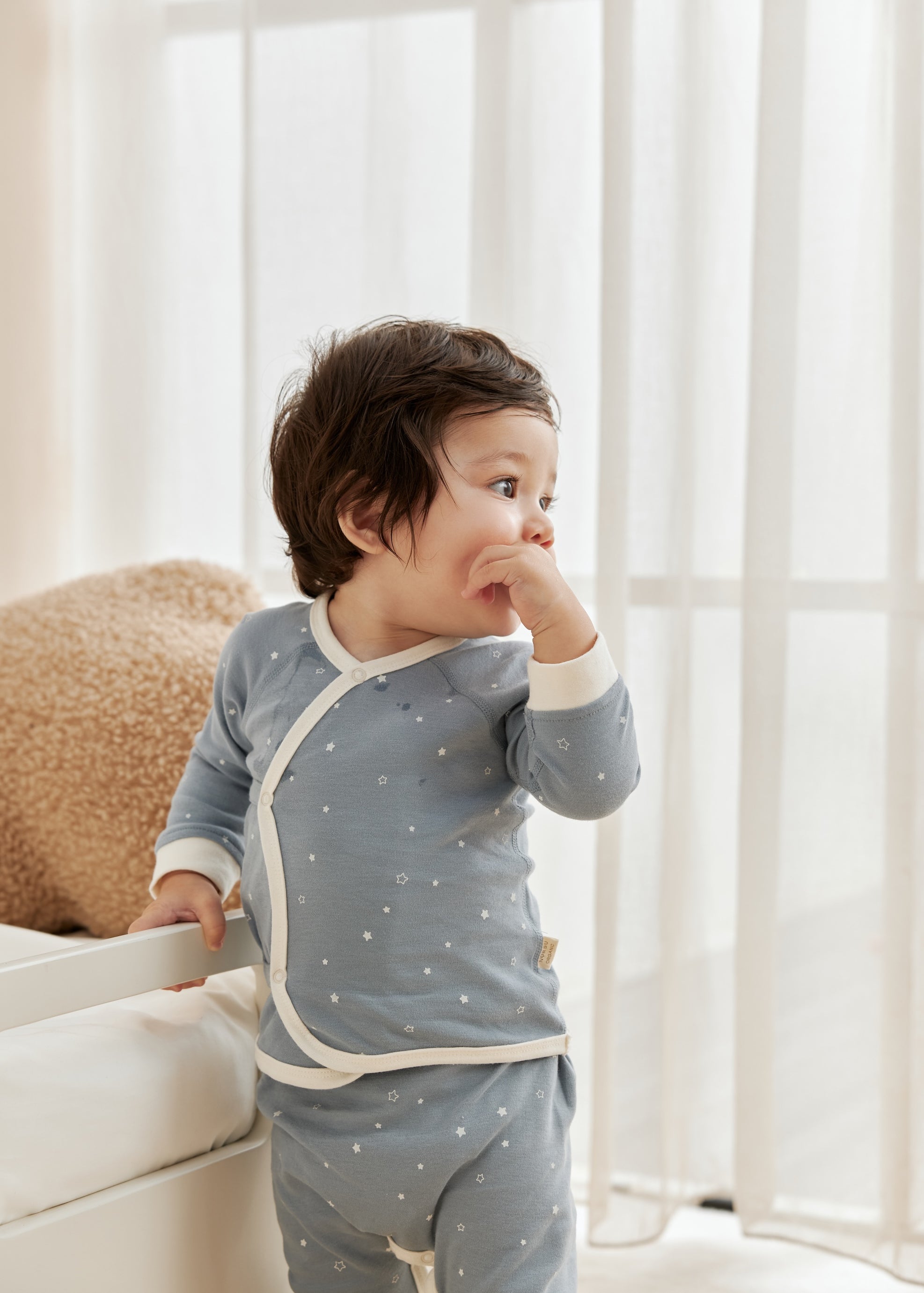 Child wearing a blue starry outfit with white trim in a bright room