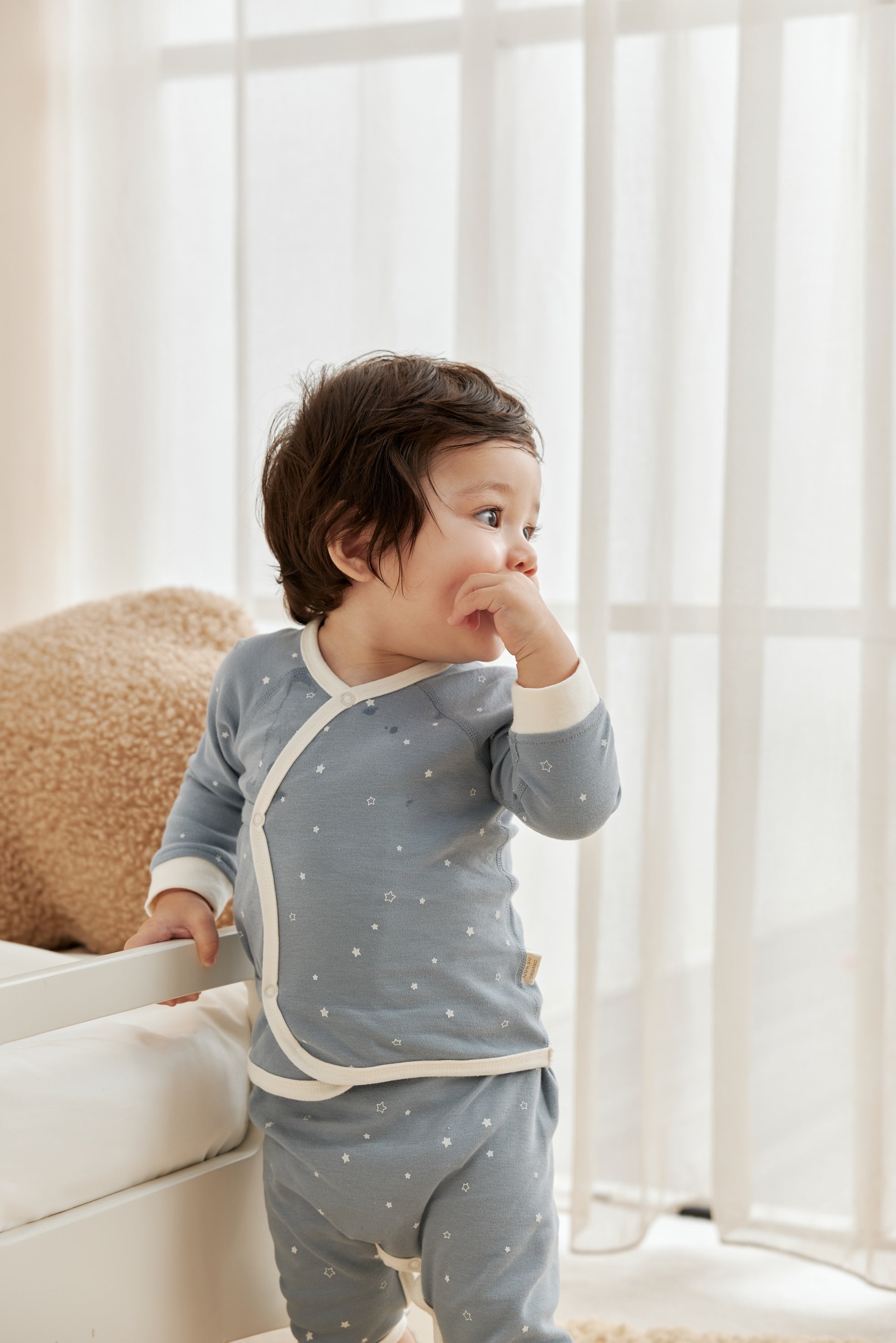 Child wearing a blue starry outfit with white trim in a bright room