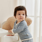 Child wearing a light blue outfit with white starry  in a bright room.