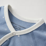 Close-up of a blue baby outfit with white trim and star pattern on a light gray background.