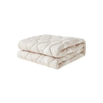 Folded beige quilt on a white background