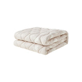 Folded beige quilt on a white background