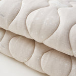 Close-up of a textured beige fabric with a subtle pattern on a light background