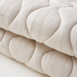 Close-up of a textured beige fabric with a subtle pattern on a light background