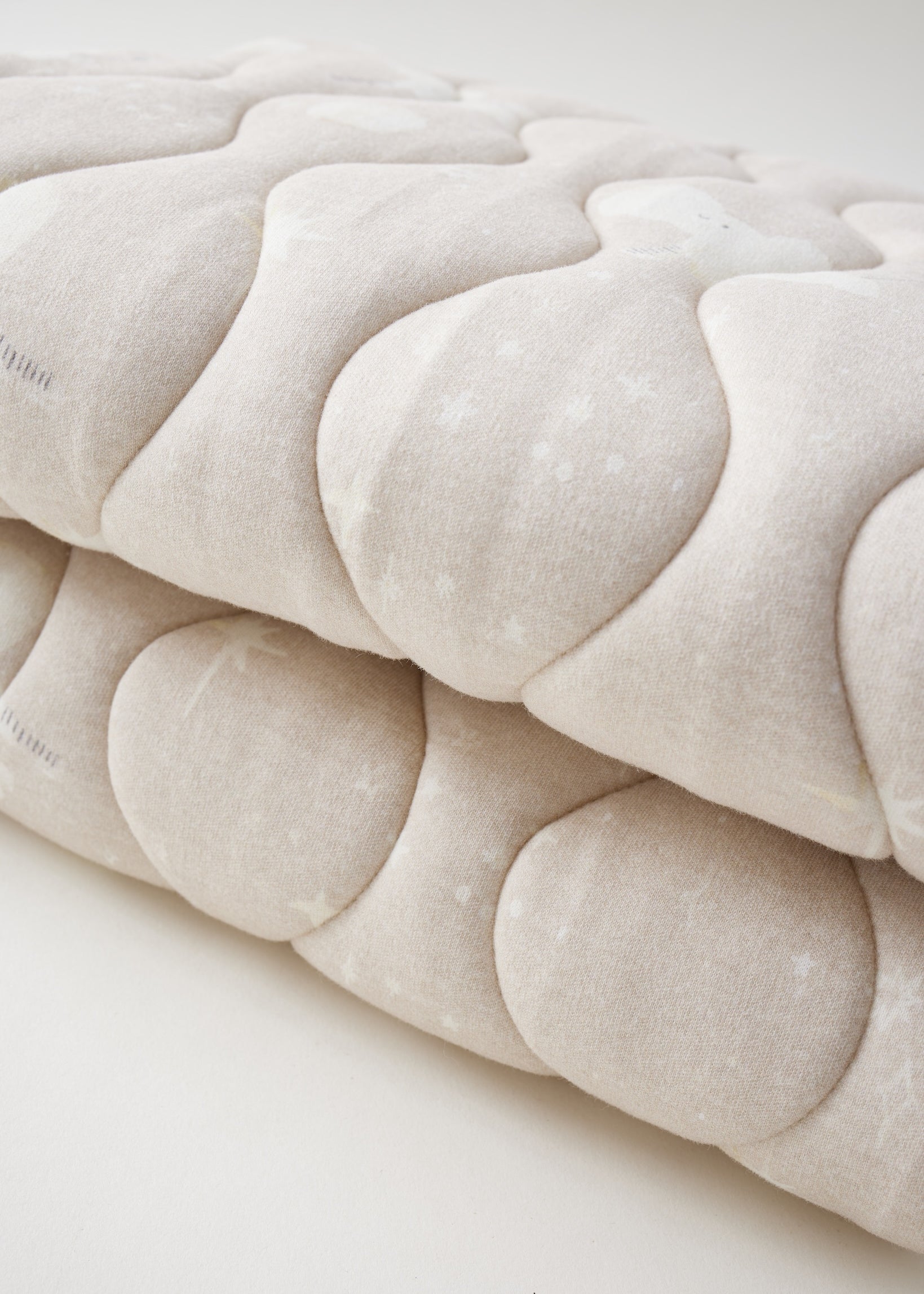 Close-up of a textured beige fabric with a subtle pattern on a light background