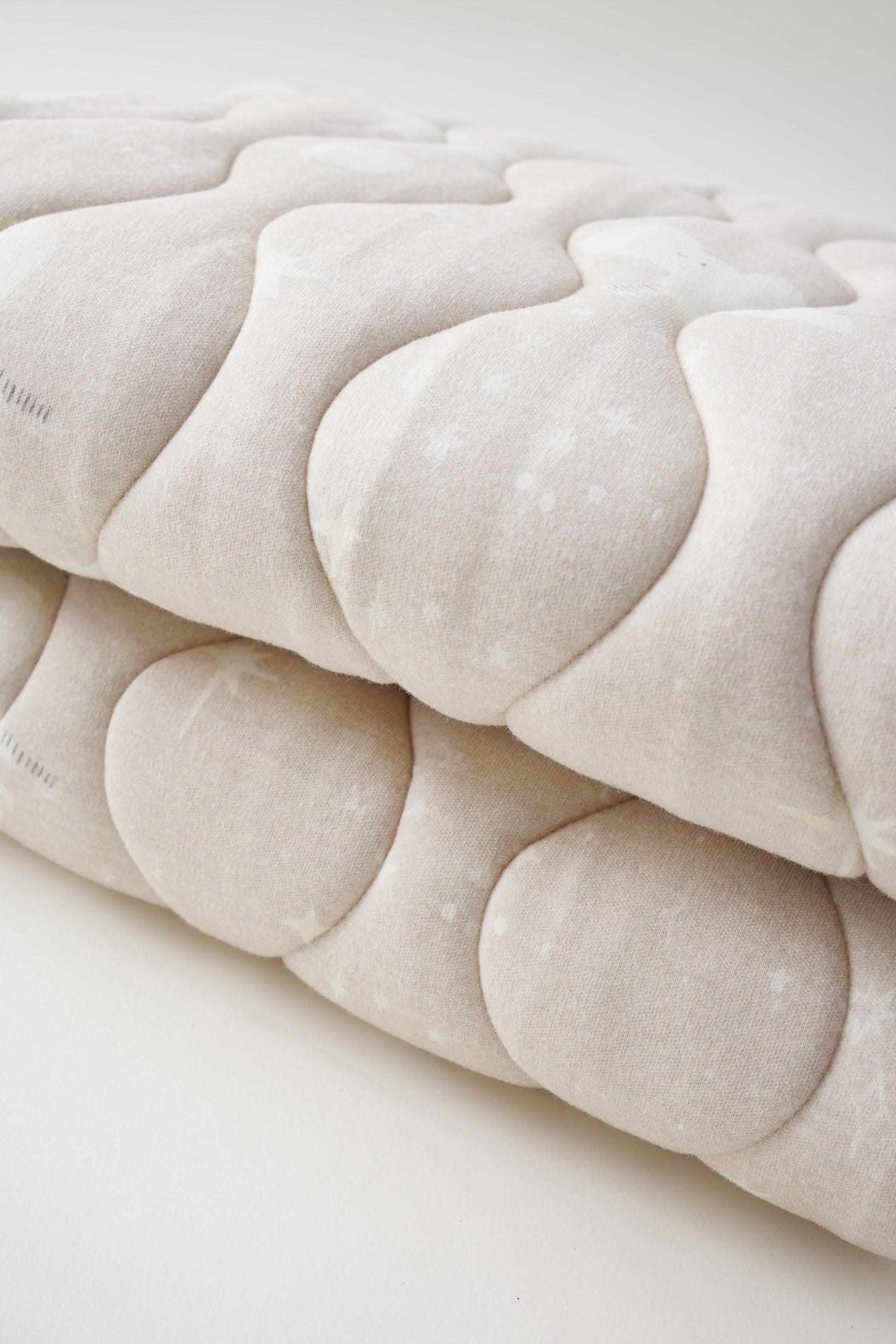 Close-up of a textured beige fabric with a subtle pattern on a light background