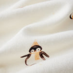 Close-up of a white fabric with small penguin illustrations.
