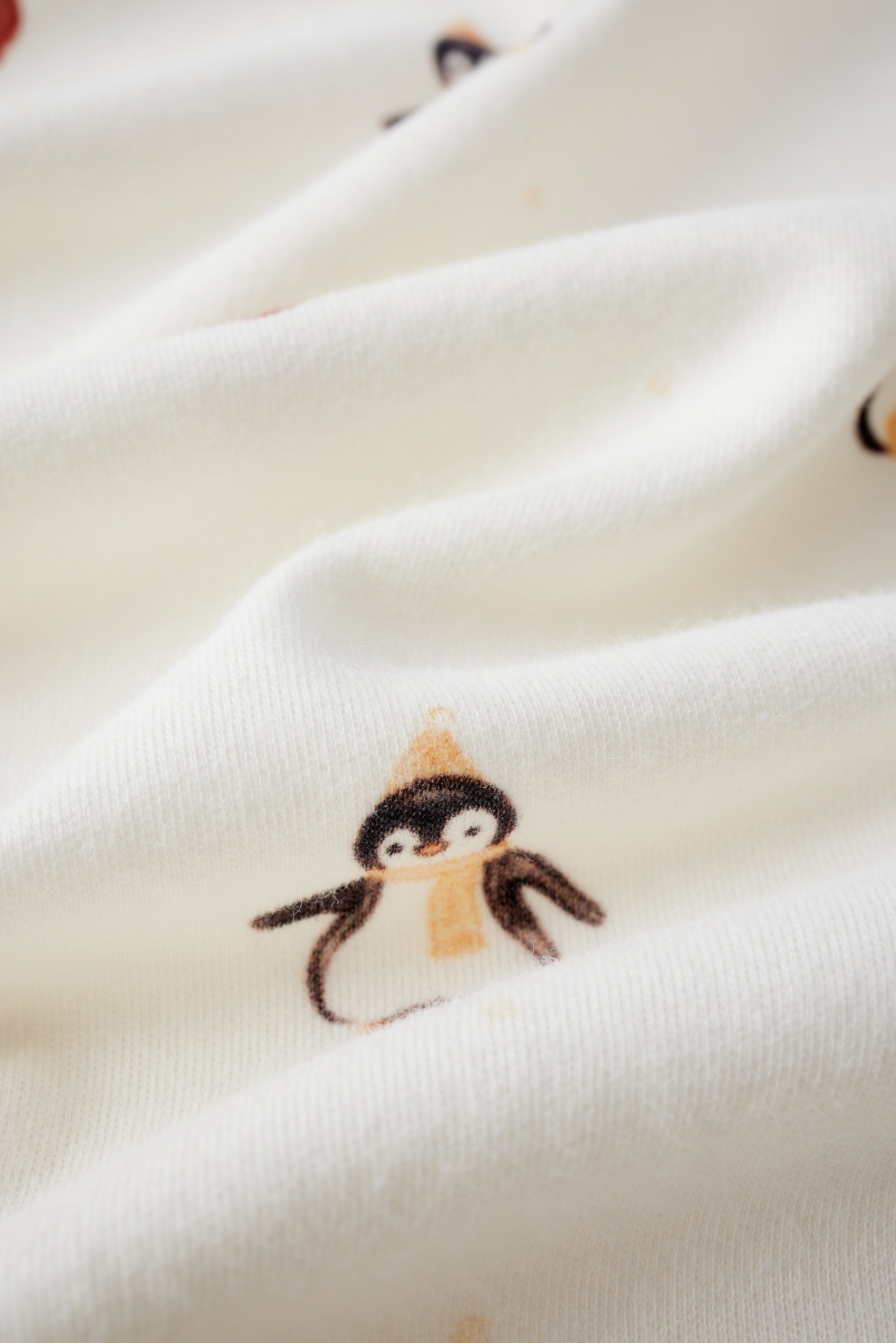 Close-up of a white fabric with small penguin illustrations.