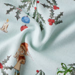 Fabric with Christmas-themed design featuring holly, berries, and a small figure on a light blue background.
