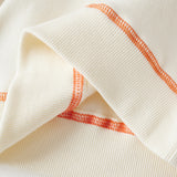 Close-up of a white garment with orange stitching on a light background