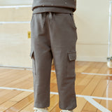 Person wearing a gray sweatshirt and cargo pants on a wooden floor.