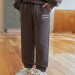 Person wearing a gray tracksuit with 'NORSU ORGANIC' branding on a wooden floor.