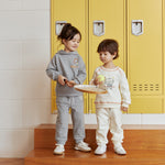 Two children standing on wooden steps in front of yellow lockers with a warning sign above.