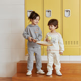 Two children standing on wooden steps in front of yellow lockers with a warning sign above.