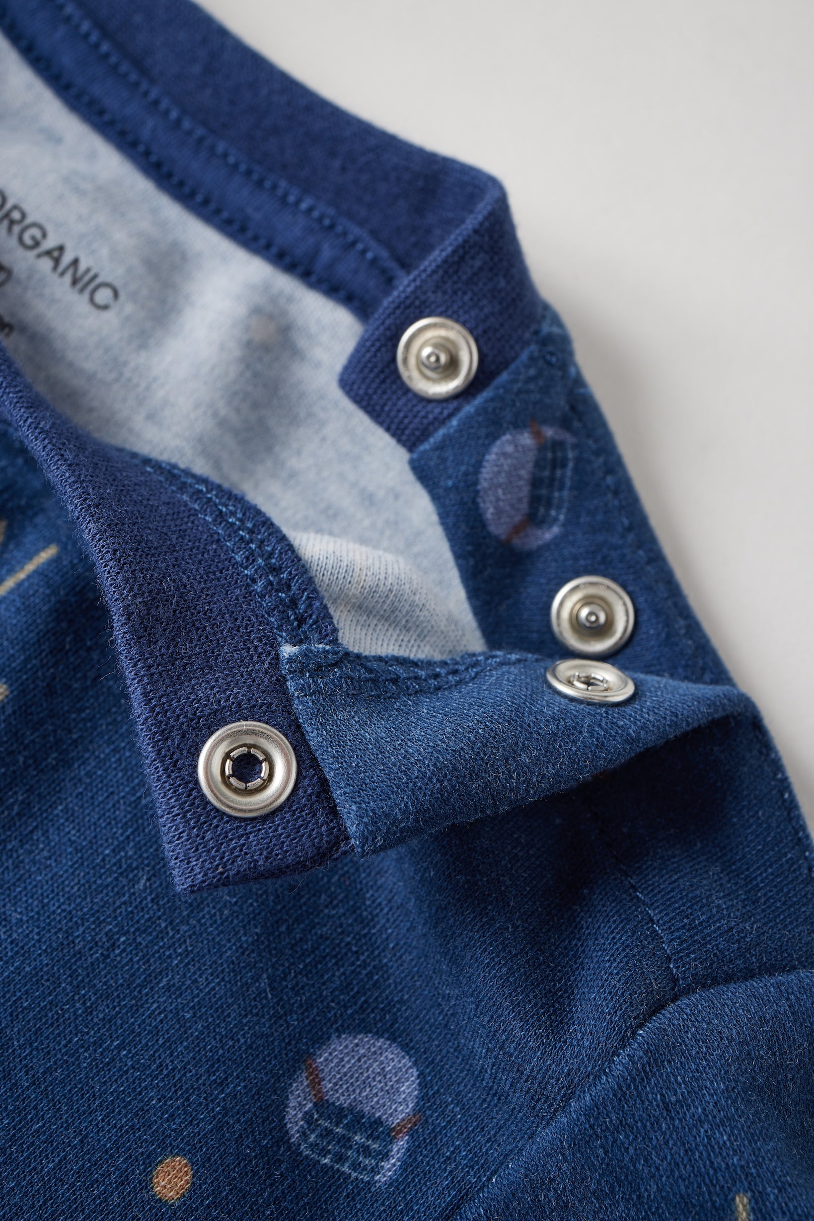 Close-up of a blue garment with buttons on a light gray background