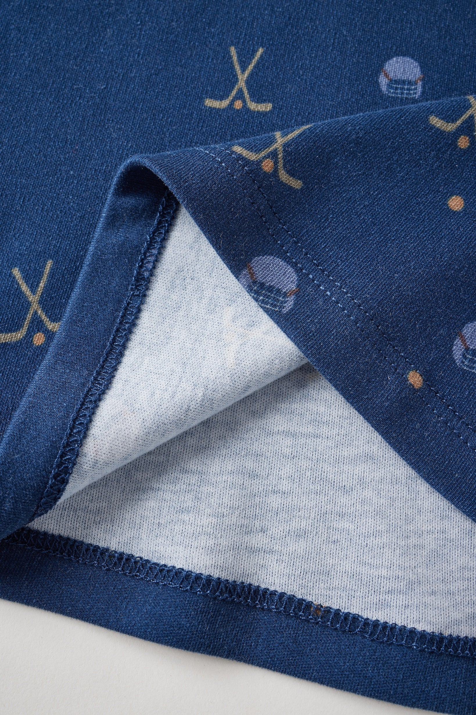 Close-up of a blue fabric with sports-themed embroidery on a white background