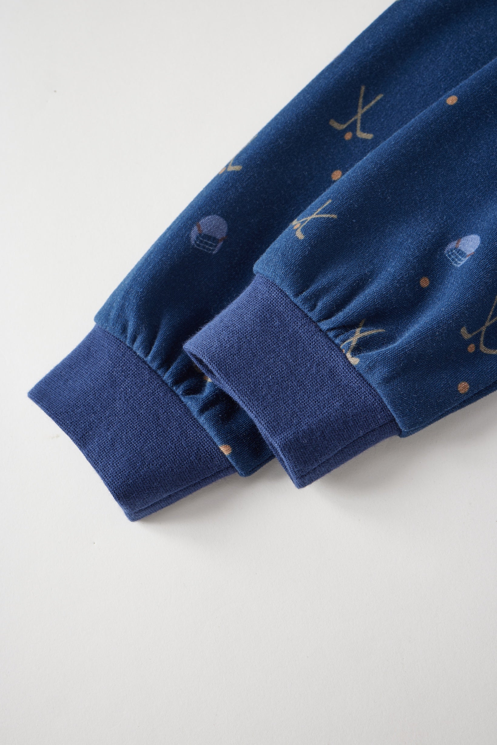 Close-up of blue fabric with embroidered designs on a light gray background