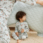 Child and adult in matching floral pajamas sitting inside a homemade cardboard box fort.