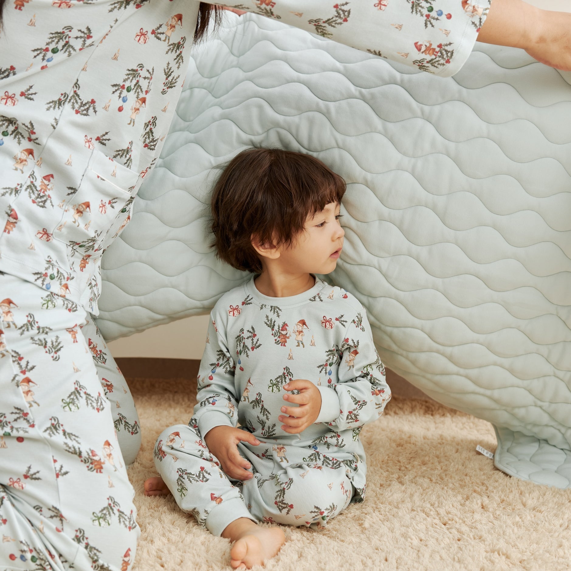 Child and adult in matching floral pajamas sitting inside a homemade cardboard box fort.