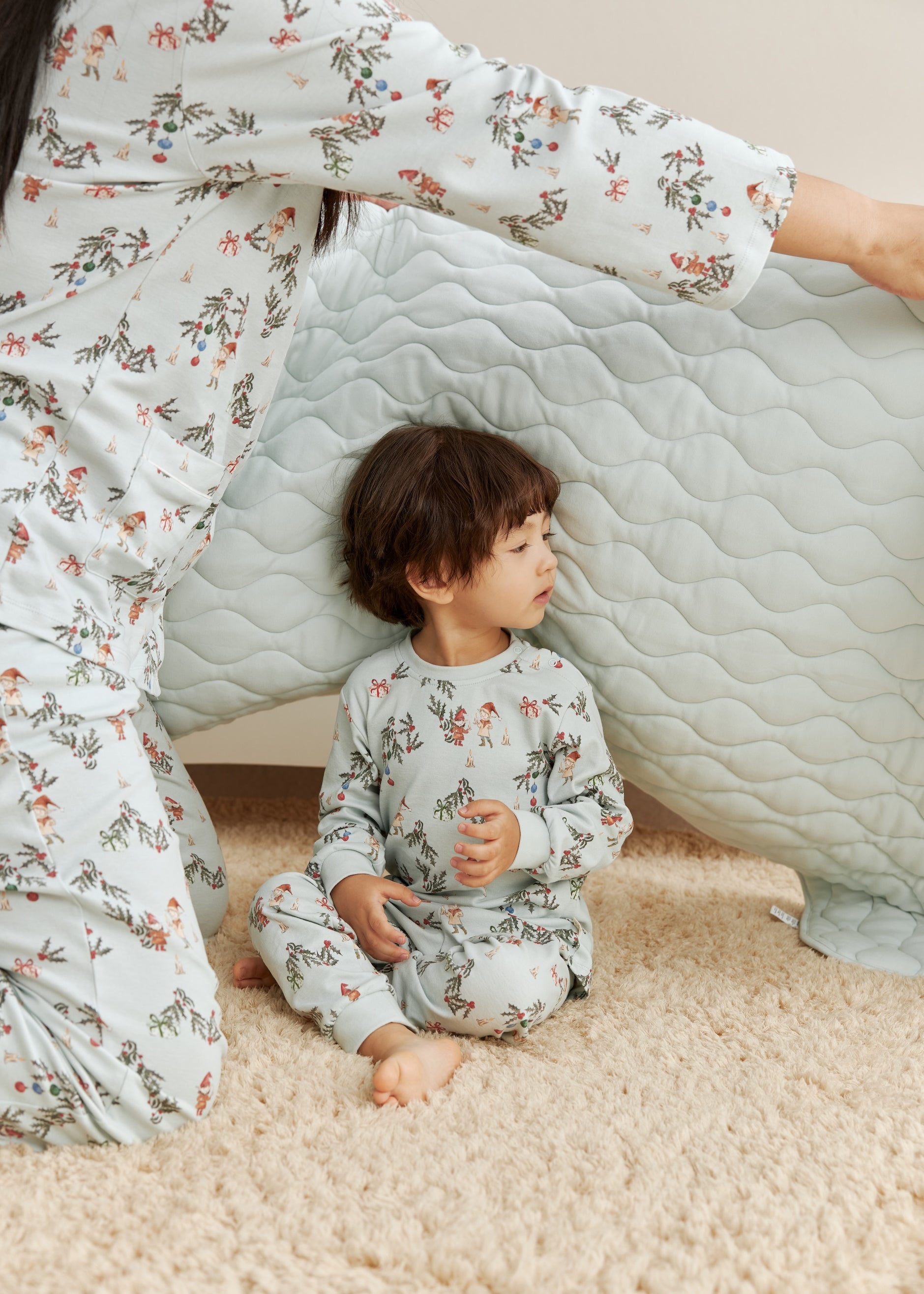 Child and adult in matching floral pajamas sitting inside a homemade cardboard box fort.