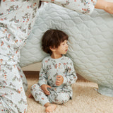 Child and adult in matching floral pajamas sitting inside a homemade cardboard box fort.