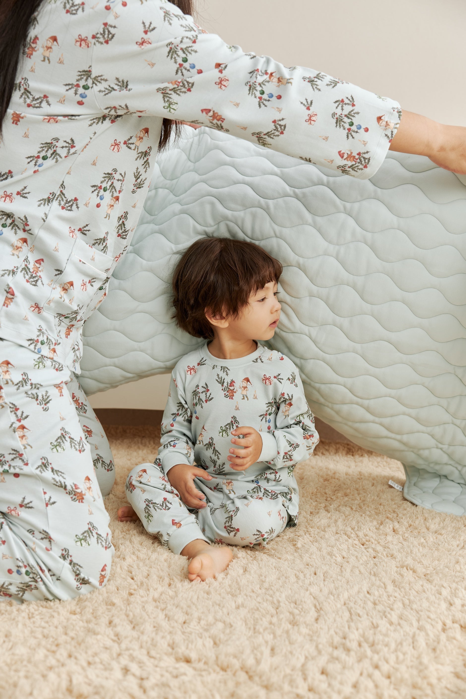 Child and adult in matching floral pajamas sitting inside a homemade cardboard box fort.