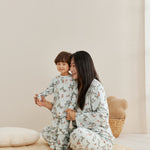 Woman and child in matching pajamas sitting on a beige rug.