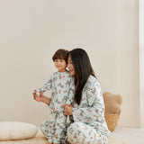 Woman and child in matching pajamas sitting on a beige rug.